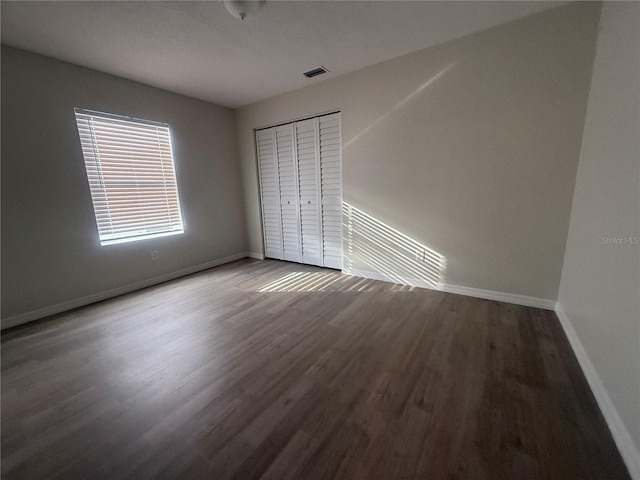 unfurnished bedroom featuring visible vents, baseboards, and wood finished floors