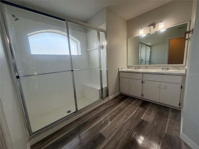 full bath featuring double vanity, wood finished floors, a sink, and a shower stall