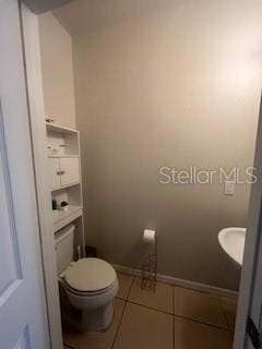 bathroom with a sink, tile patterned flooring, toilet, and baseboards