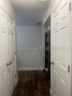 corridor with baseboards and dark wood-type flooring