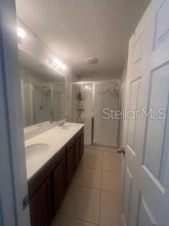 full bathroom with double vanity, a sink, a shower stall, and tile patterned floors