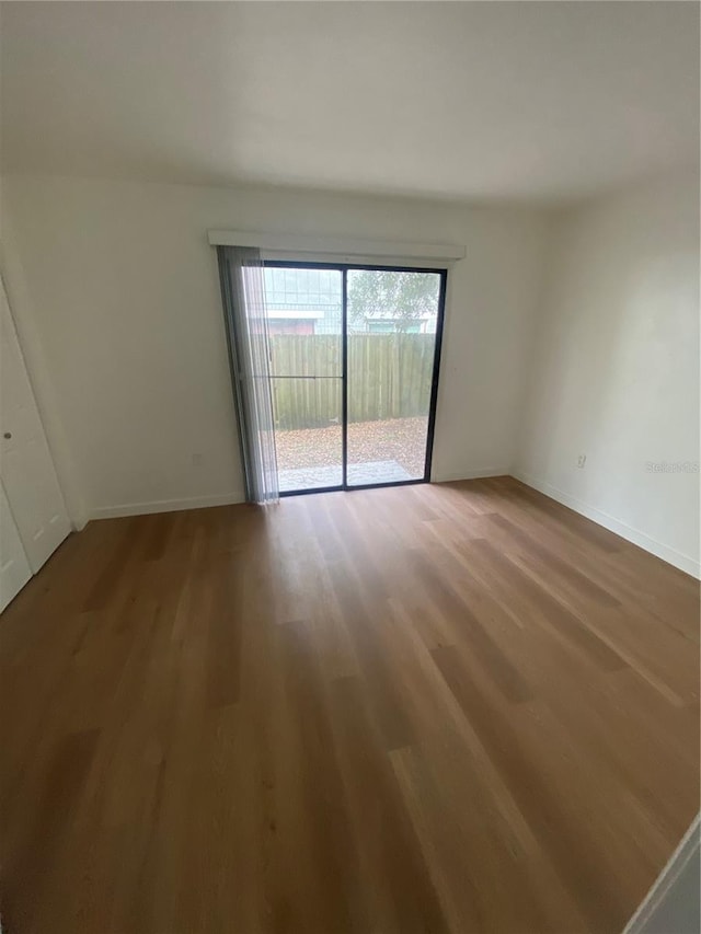 spare room with baseboards and wood finished floors