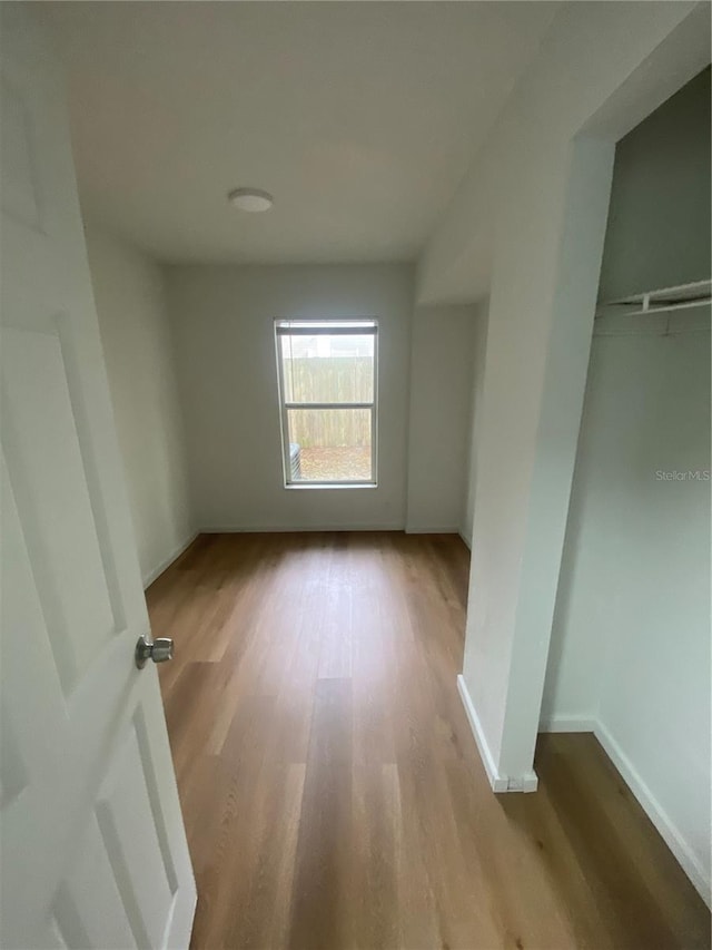 unfurnished bedroom featuring light wood-type flooring, a closet, and baseboards