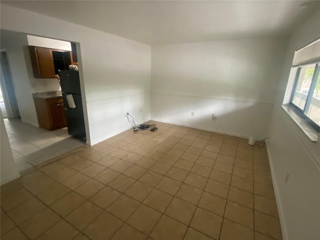 empty room with baseboards and light tile patterned flooring