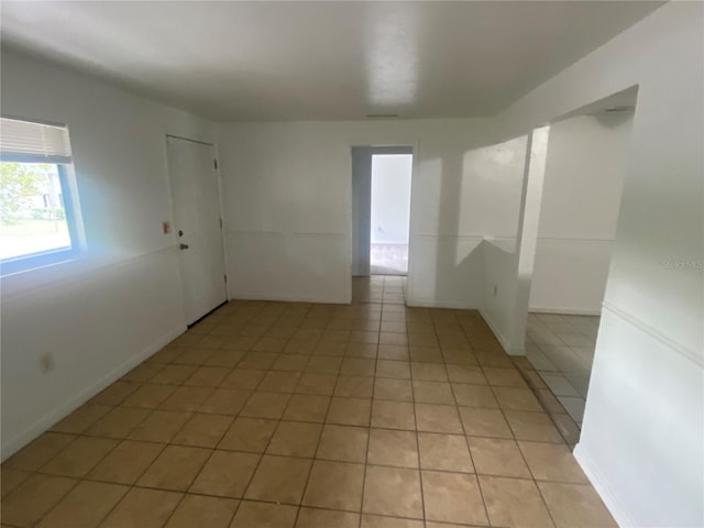 empty room with light tile patterned flooring and baseboards