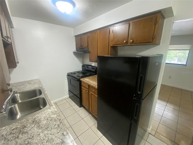 kitchen with light tile patterned floors, under cabinet range hood, a sink, baseboards, and black appliances