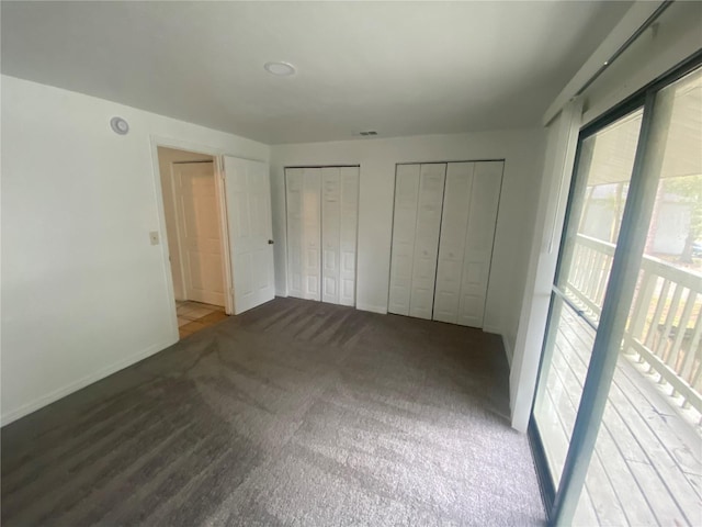 unfurnished bedroom featuring multiple closets, carpet flooring, visible vents, and baseboards