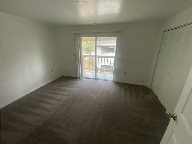 interior space with baseboards and dark carpet