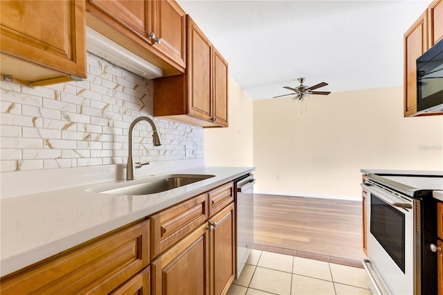 1695 Lee Rd Unit E103, Winter Park, FL 32789 - kitchen with a sink, range with electric cooktop, tasteful backsplash, ceiling fan, and brown cabinets