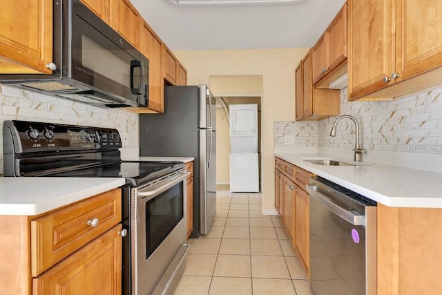 1695 Lee Rd Unit E103, Winter Park, FL 32789 - kitchen with stainless steel appliances, estacked washer and dryer, a sink, tasteful backsplash, and light tile patterned flooring