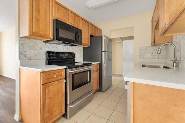 1695 Lee Rd Unit E103, Winter Park, FL 32789 - kitchen featuring stacked washer / dryer, a sink, stainless steel appliances, tasteful backsplash, and light countertops