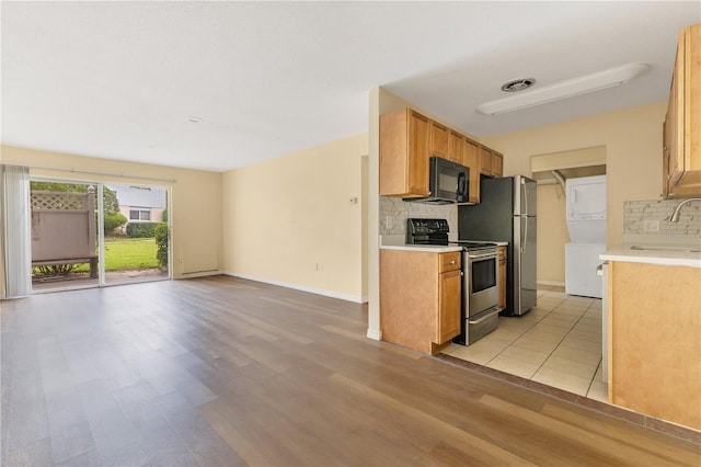 1695 Lee Rd Unit E103, Winter Park, FL 32789 - kitchen with electric range, stacked washer and clothes dryer, black microwave, backsplash, and a sink