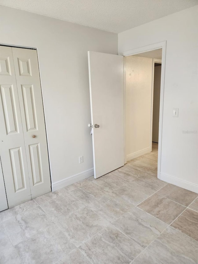 empty room with a textured ceiling and baseboards