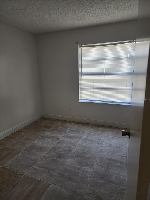 empty room with baseboards and a textured ceiling