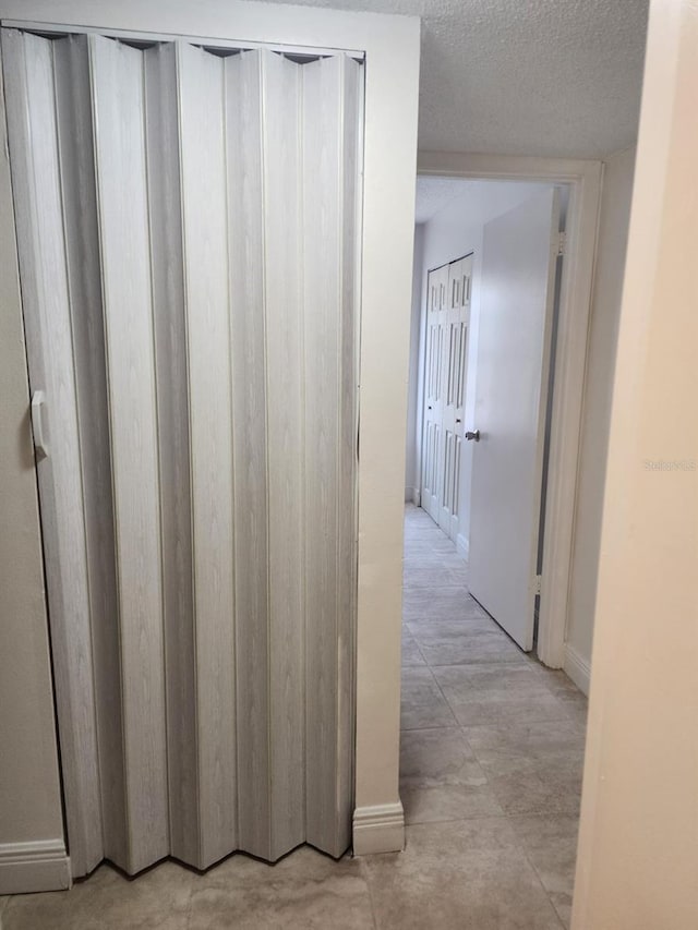 corridor with baseboards and a textured ceiling