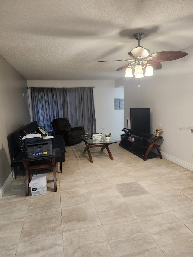 living area featuring a ceiling fan, a textured ceiling, and baseboards