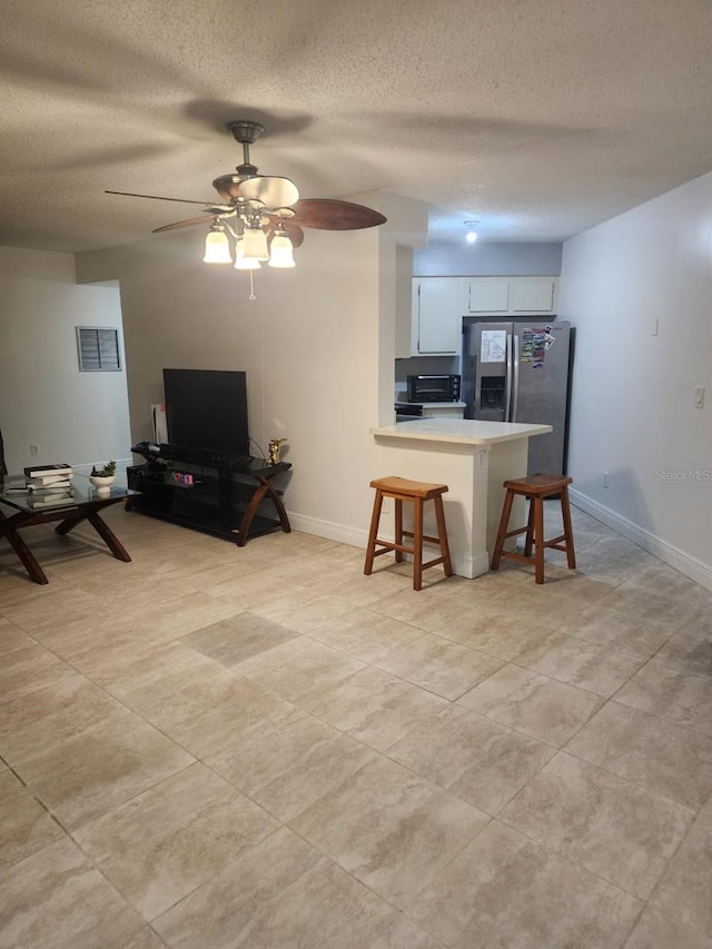 kitchen with white cabinets, open floor plan, a kitchen breakfast bar, a peninsula, and light countertops