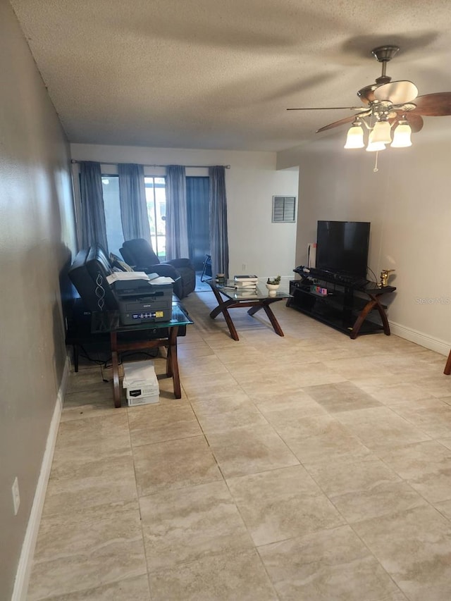 living room featuring a textured ceiling, a ceiling fan, visible vents, and baseboards