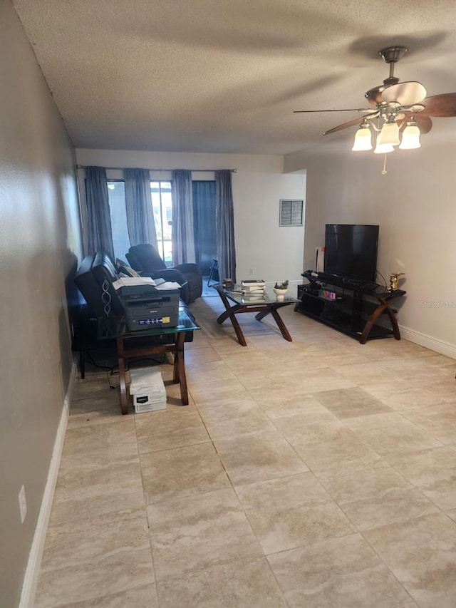 living area featuring visible vents, ceiling fan, a textured ceiling, and baseboards