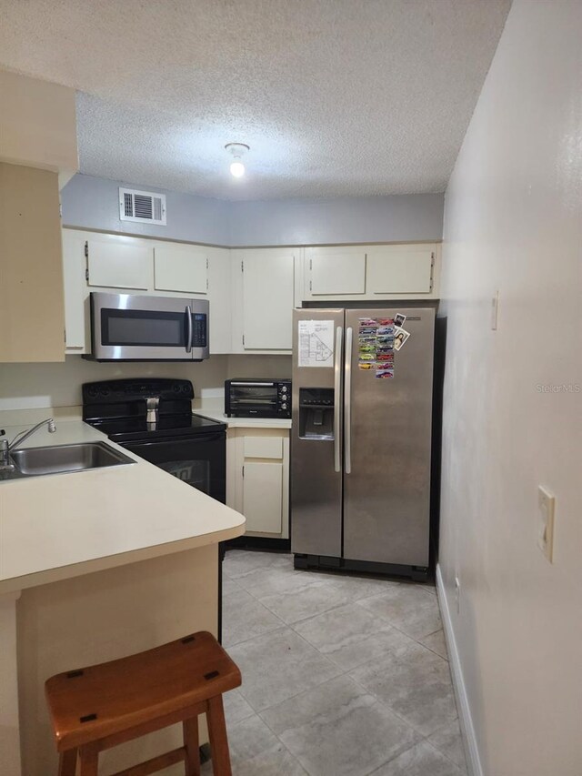 kitchen with stainless steel appliances, light countertops, visible vents, a sink, and a textured ceiling