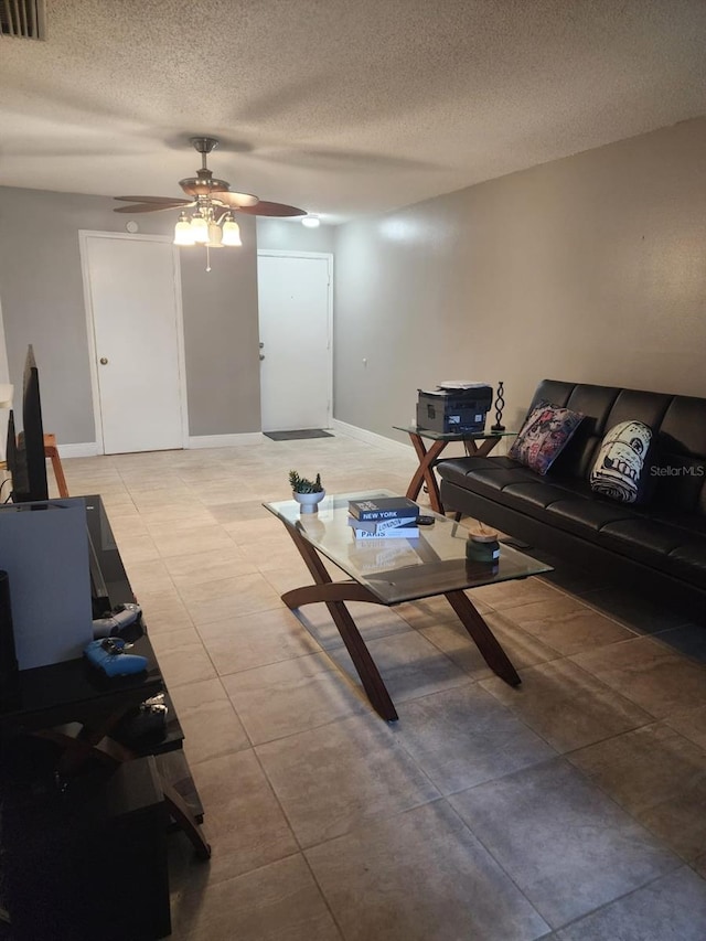 living room with a ceiling fan, visible vents, a textured ceiling, and light tile patterned floors