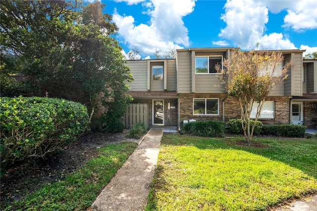 townhome / multi-family property featuring a front lawn and brick siding