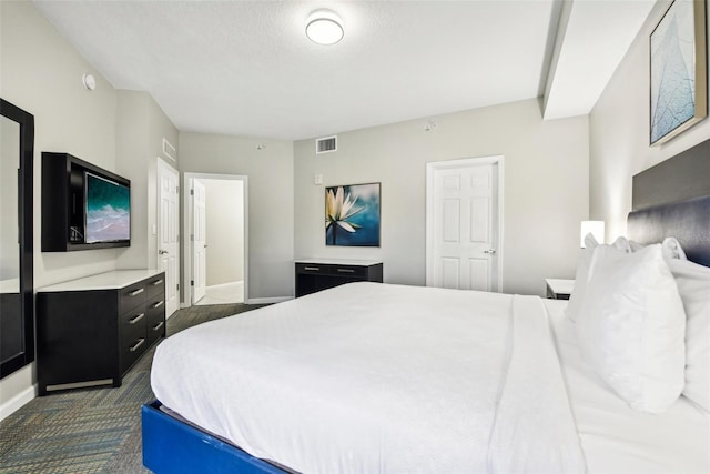 bedroom featuring dark colored carpet, visible vents, a textured ceiling, and baseboards