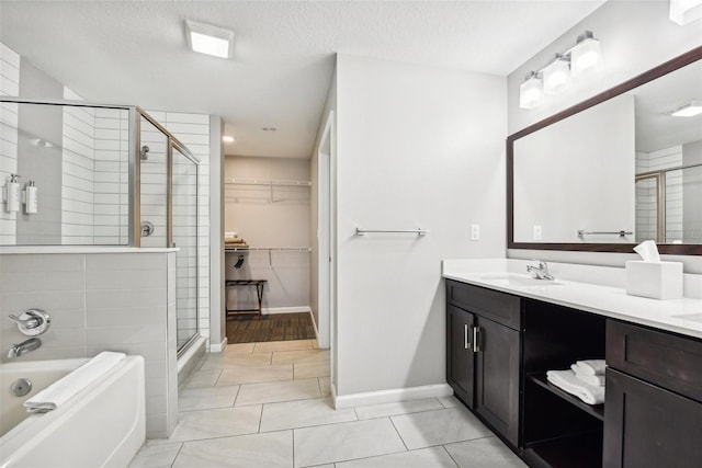 bathroom with a textured ceiling, a garden tub, a sink, a spacious closet, and a shower stall