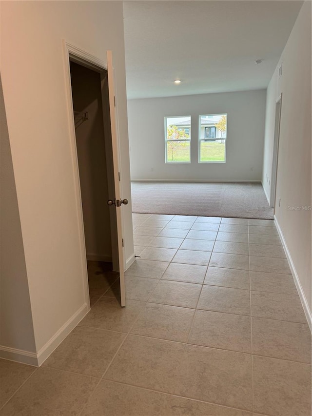 hall featuring baseboards and light tile patterned floors