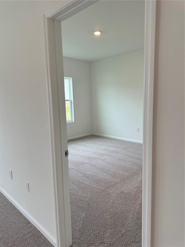 carpeted empty room featuring baseboards