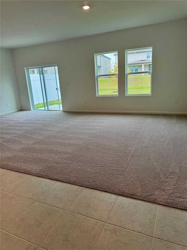 spare room featuring light carpet, a wealth of natural light, and baseboards