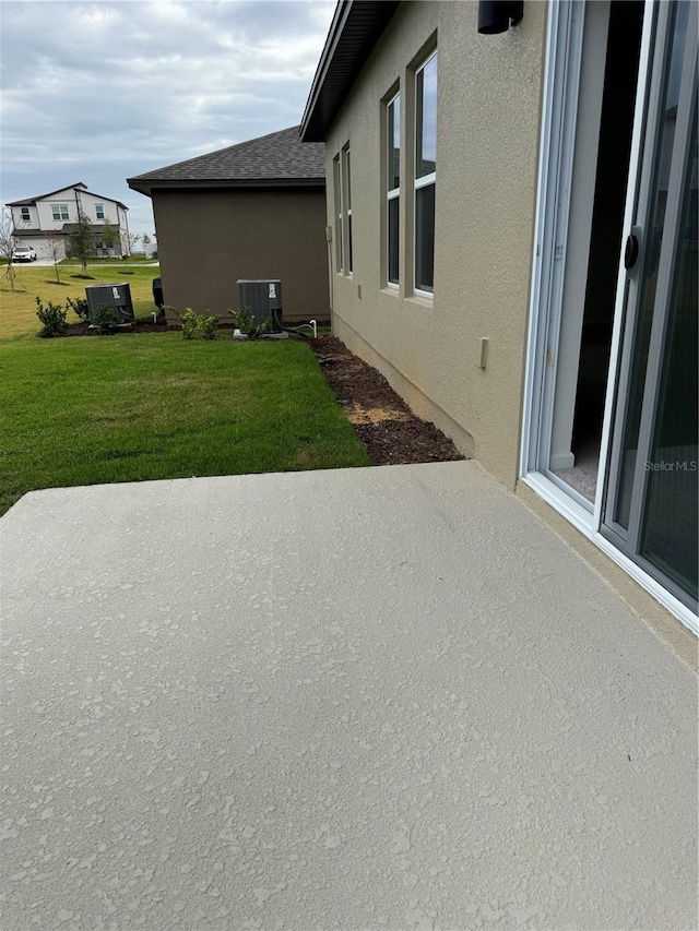 view of property exterior with central AC unit, roof with shingles, a yard, a patio area, and stucco siding