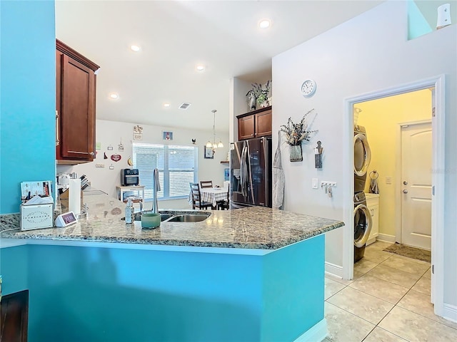 649 Meadow Pointe Dr, Haines City, FL 33844 - kitchen featuring stacked washer and dryer, light tile patterned floors, a peninsula, stainless steel refrigerator with ice dispenser, and a sink