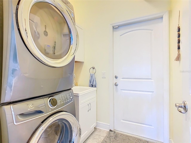649 Meadow Pointe Dr, Haines City, FL 33844 - laundry area featuring light tile patterned floors, cabinet space, stacked washer and clothes dryer, and baseboards