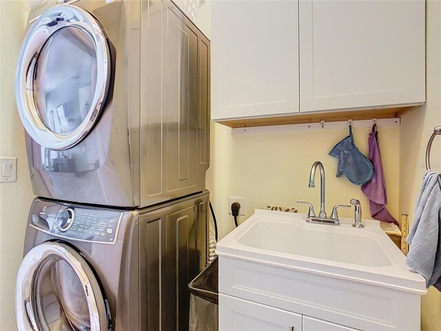 649 Meadow Pointe Dr, Haines City, FL 33844 - laundry room featuring stacked washer / dryer, cabinet space, and a sink