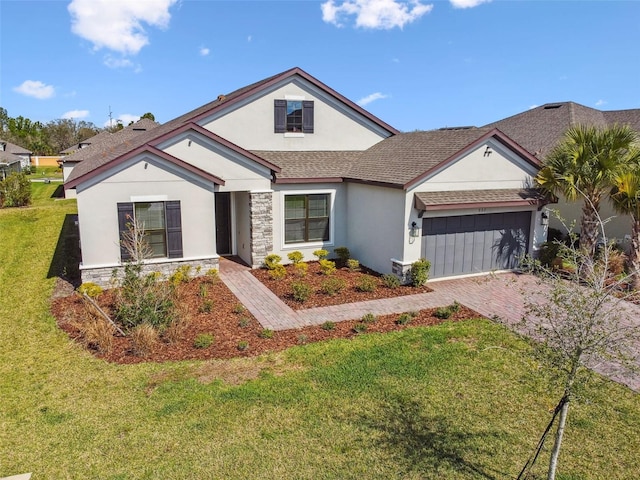 view of front of property featuring decorative driveway, stucco siding, an attached garage, a front yard, and stone siding