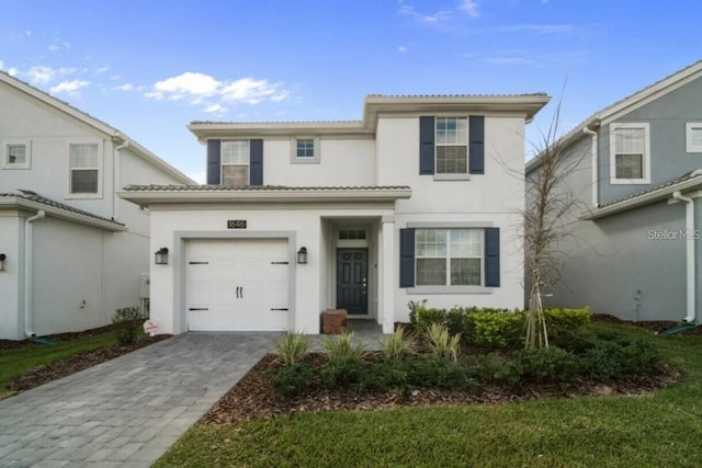 view of front of house featuring a garage, decorative driveway, and stucco siding