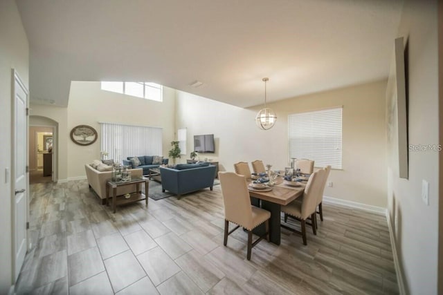 dining room with a chandelier, arched walkways, a towering ceiling, and baseboards