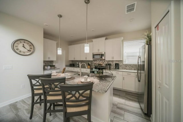 1646 Moon Valley Dr, Davenport, FL 33896 - kitchen featuring stainless steel appliances, decorative backsplash, visible vents, and white cabinetry