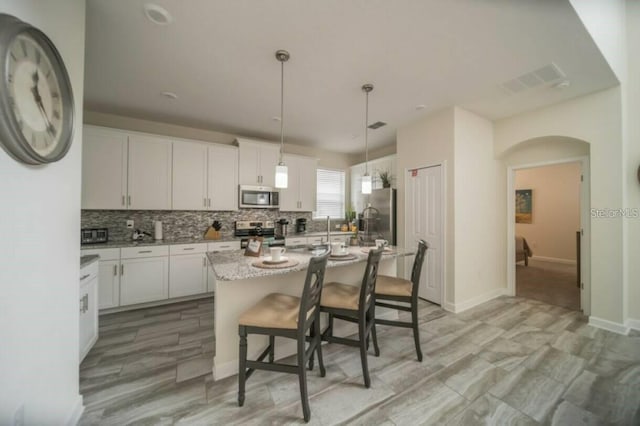 1646 Moon Valley Dr, Davenport, FL 33896 - kitchen featuring stainless steel appliances, white cabinetry, visible vents, and decorative backsplash