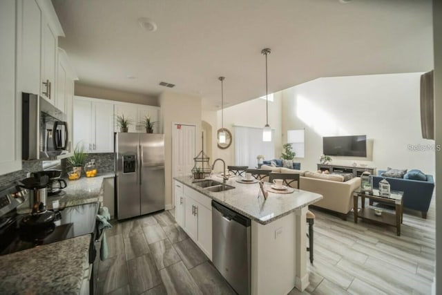 1646 Moon Valley Dr, Davenport, FL 33896 - kitchen featuring a breakfast bar, a sink, appliances with stainless steel finishes, decorative backsplash, and a center island with sink