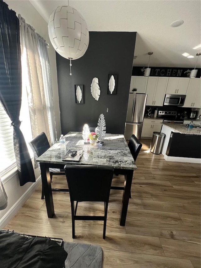 dining room featuring a healthy amount of sunlight, baseboards, and wood finished floors