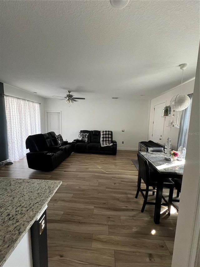 living area featuring ceiling fan, a textured ceiling, and dark wood-type flooring