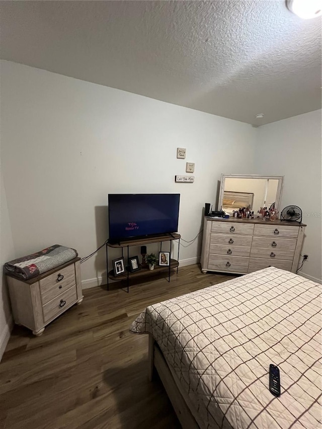 bedroom with baseboards, dark wood finished floors, and a textured ceiling