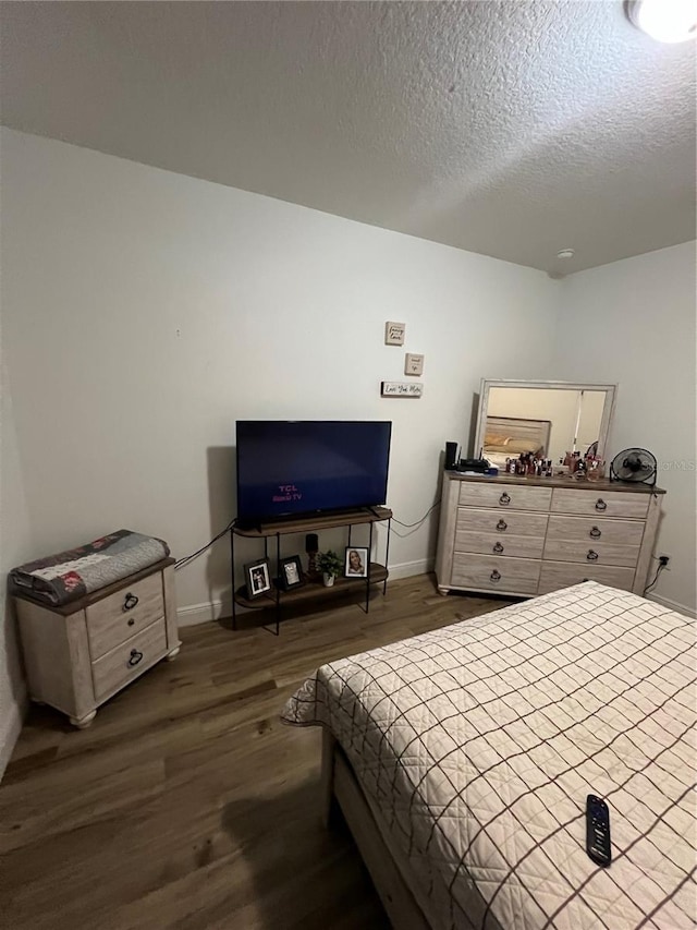 bedroom featuring dark wood-style floors, baseboards, and a textured ceiling