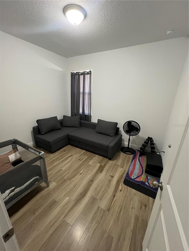 living area with light wood-style flooring, baseboards, and a textured ceiling