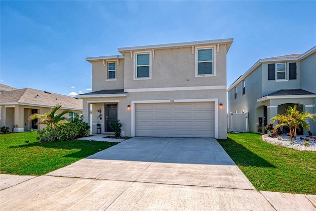 traditional-style home with a garage, driveway, a front yard, and stucco siding