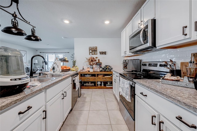 kitchen with light tile patterned floors, stainless steel appliances, tasteful backsplash, white cabinetry, and a sink