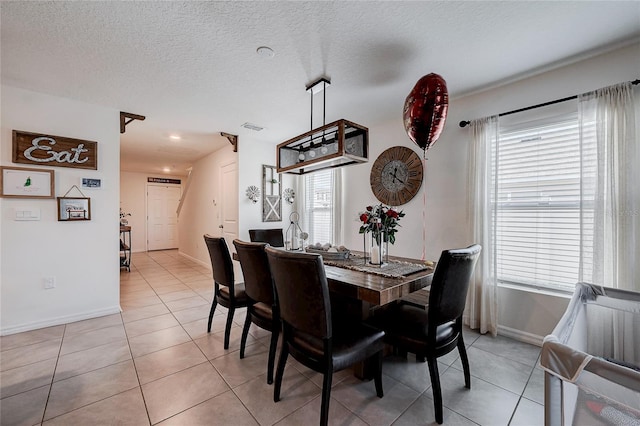 dining area with light tile patterned floors, visible vents, baseboards, and a textured ceiling