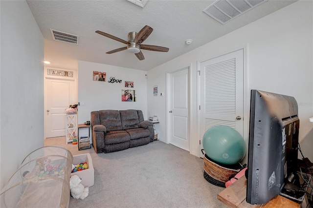 interior space with ceiling fan, a textured ceiling, carpet, and visible vents